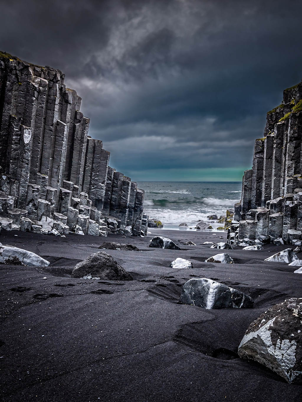 Basalt column cliffs and white Atlantic foam on black volcanic sand