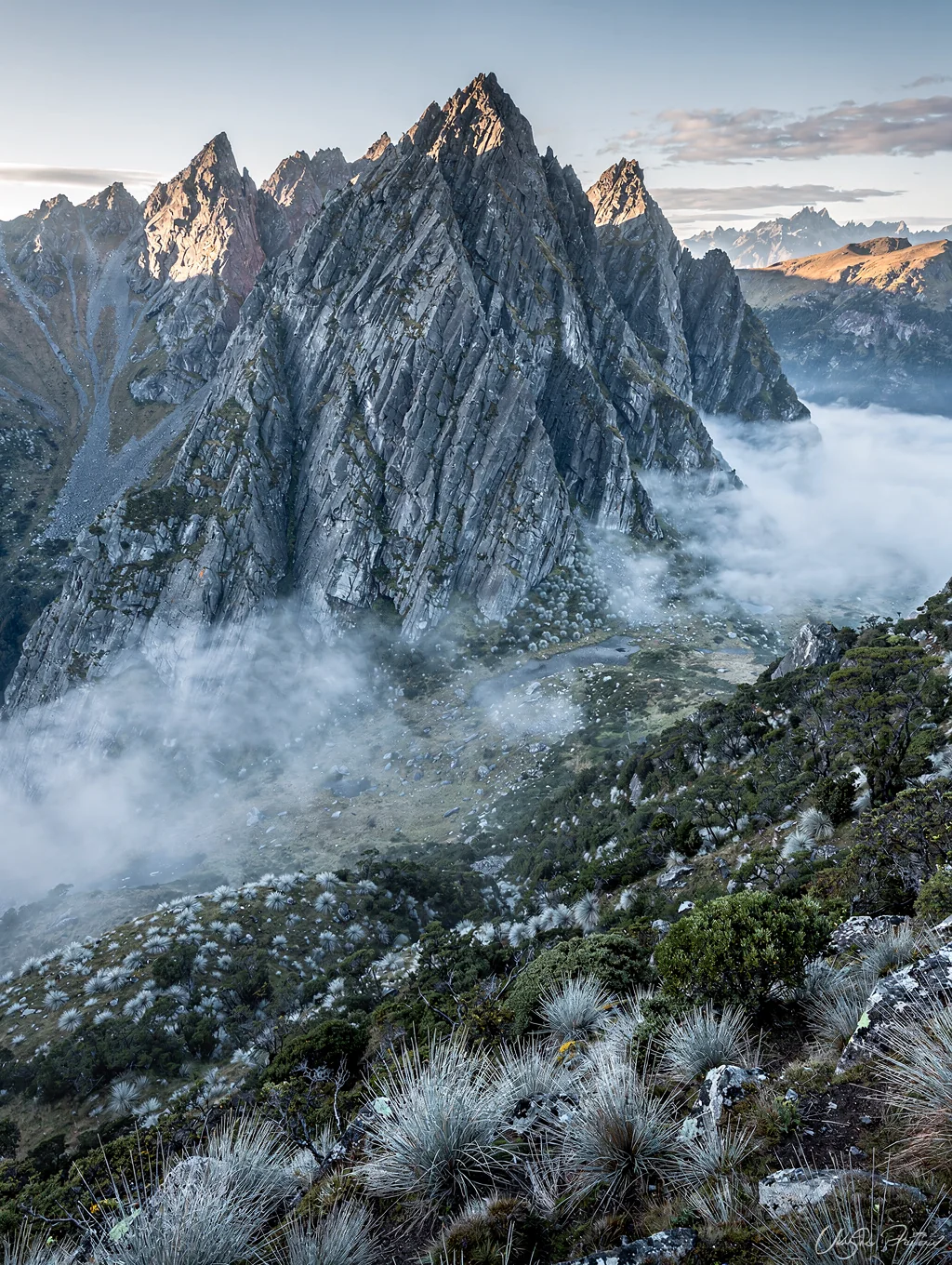Vertical granite mountain ridge rising above alpine mist in New Zealand